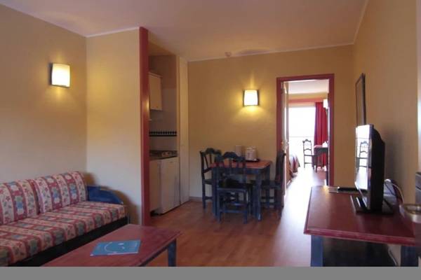 Innenraum des Hovima Jardin Caleta Hotels mit Wohnzimmer, Esstisch und Fernseher.