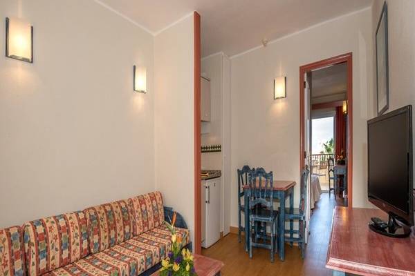 Wohnbereich des Hovima Jardin Caleta Hotels mit Sofa, Tisch, Fernseher und Esstisch.