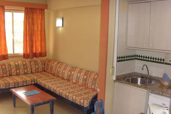 Wohnbereich im Hovima Jardin Caleta Hotel mit einem gemusterten Sofa, einem Tisch und einer Küche