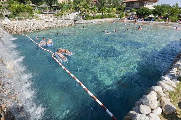 Gäste genießen den Poolbereich des Club Grand Side Hotels mit vielen Schwimmern und grüner Umgebung.