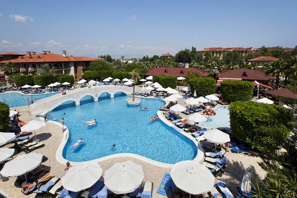Luftaufnahme des Club Grand Side Pools mit Gästen, Liegestühlen und Sonnenschirmen.