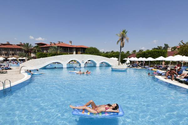 Schwimmbad des Club Grand Side Hotels mit einer Brücke und vielen Gästen.