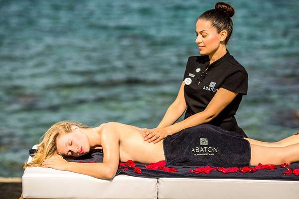 Frau genießt eine Massage am Strand im Abaton Island Resort & Spa