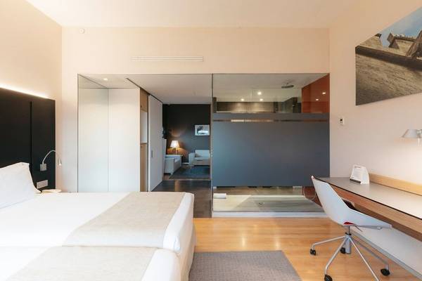 Innenansicht eines Hotelzimmers im Barcelo Valencia mit Doppelbett, Schreibtisch und moderner Einrichtung.