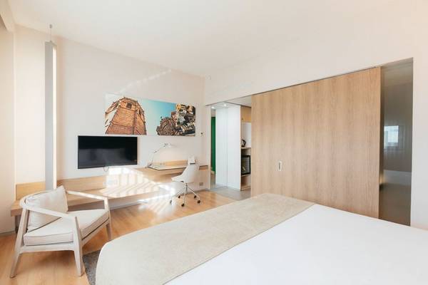 Innenansicht des Barcelo Valencia Hotels mit einem Bett, Schreibtisch und Fernseher.