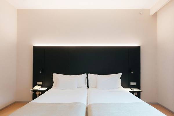 Zwei moderne Doppelbetten mit weißen Kissen in einem stilvollen Hotelzimmer im Barcelo Valencia.