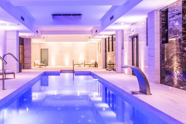 Schwimmbecken im Abaton Island Resort & Spa Hotel mit blauer Beleuchtung und Loungebereich