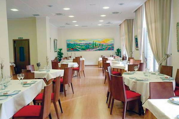 Innenansicht des Restaurants des DWO Valencia mit gedeckten Tischen und Stühlen, Gemälde an der Wand.