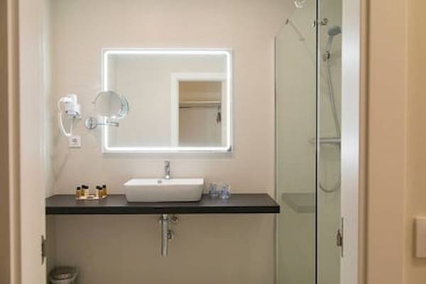 Badezimmer im DWO Valencia mit Waschbecken, Spiegel und Duschbereich