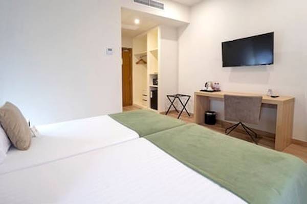 Zweibettzimmer im DWO Valencia Hotel mit grünen Decken und Fernseher an der Wand.