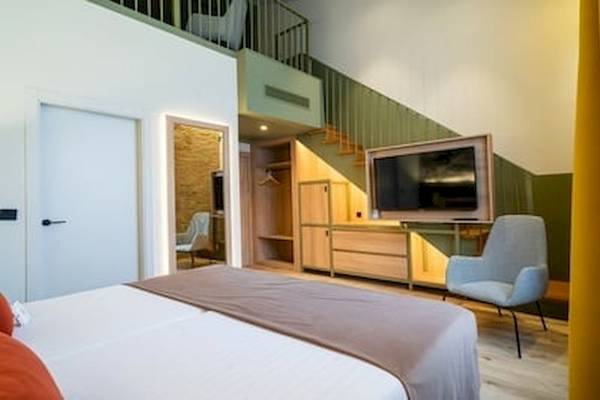 Hotelzimmer des DWO Valencia mit Bett, Stuhl und Fernseher.