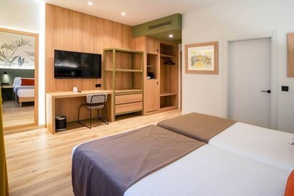 Doppelzimmer im DWO Valencia Hotel mit zwei Betten, Schreibtisch, Fernseher und Kleiderschrank.