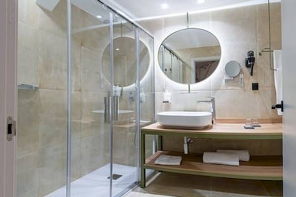 Badezimmer im DWO Valencia Hotel mit ebenerdiger Dusche, Waschbecken und Spiegeln.