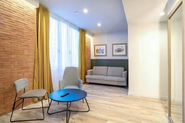 Innenraum des DWO Valencia Hotels mit grauem Sofa, blauem Tisch und zwei Stühlen.