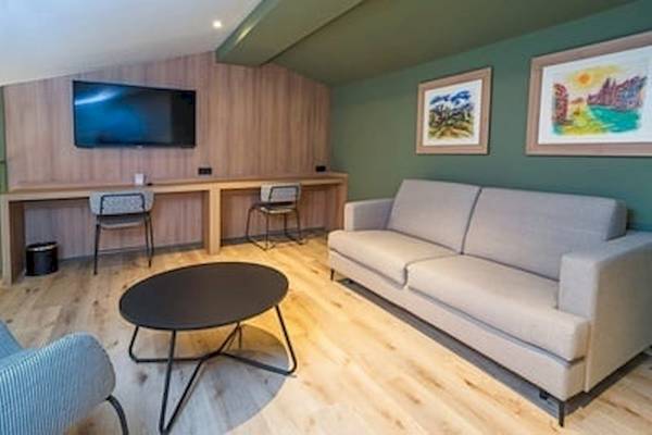 Inneneinrichtung des DWO Valencia Hotels mit Fernseher, Sofa, Tisch und Gemälden an der Wand.