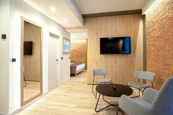 Hotelzimmer mit Fernseher, Bett, Spiegel, zwei Stühlen und einem Tisch