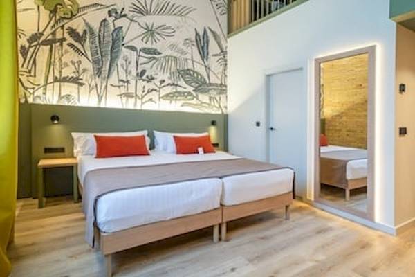 Schlafzimmer im DWO Valencia Hotel mit zwei Einzelbetten, grün-weißer Wandgestaltung und offenem Badezimmer