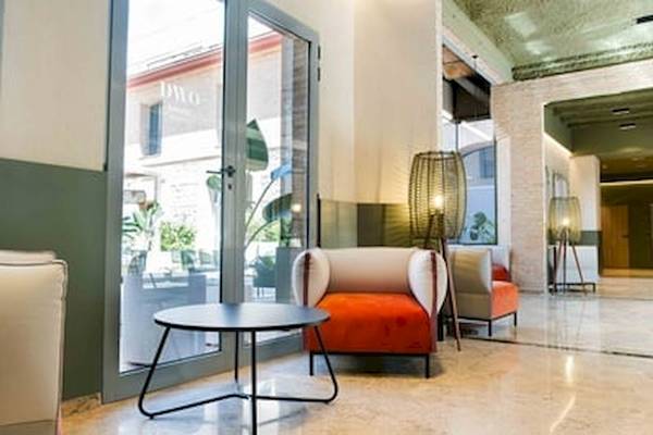 Hotellobby des DWO Valencia mit modernen Möbeln, einem Glastisch und großen Fenstern.