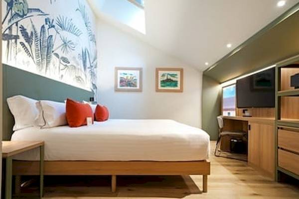 Ein Schlafzimmer im DWO Valencia Hotel mit einem Bett, Kissen, Gemälden und einem Fernseher.
