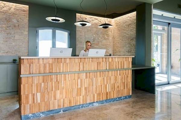 Rezeption des DWO Valencia Hotels mit einer Frau, die an zwei Laptops arbeitet.