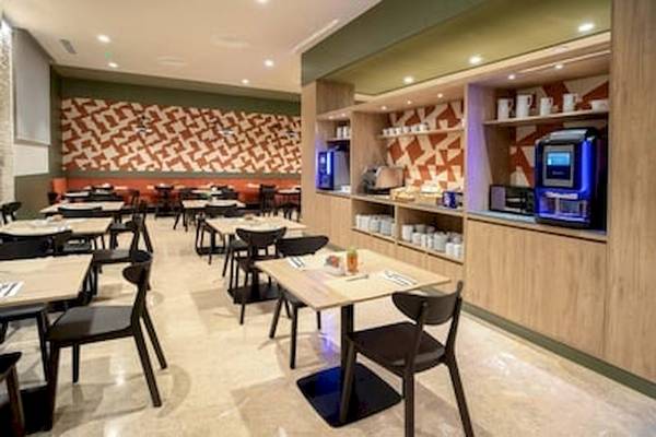 Frühstücksraum des DWO Valencia Hotels mit Tischen, Stühlen und einer Kaffeemaschine.