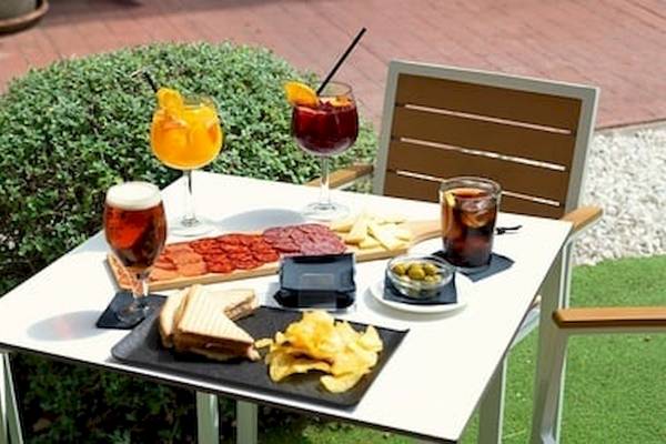 Ein Tisch im Garten des DWO Valencia Hotels mit Getränken und Essen.