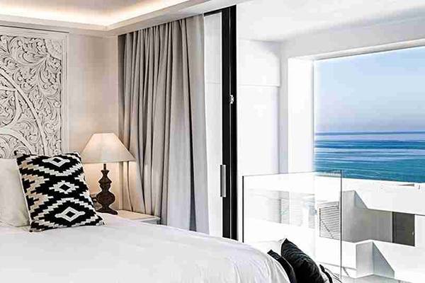 Schlafzimmer mit Meerblick im Abaton Island Resort & Spa mit gemusterten Kissen und Panoramafenster.