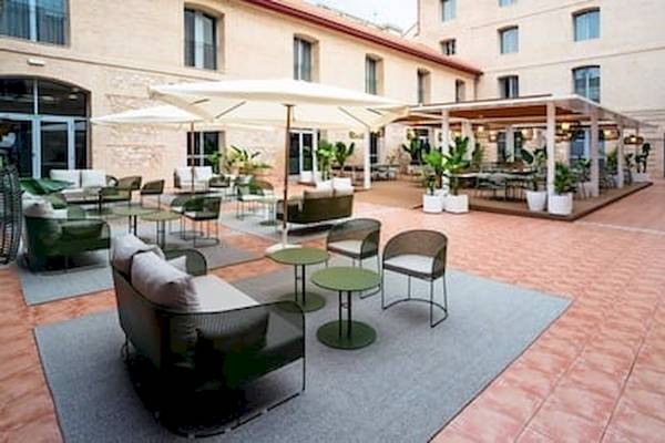 Außenbereich des DWO Valencia Hotels mit Tischen, Stühlen und Pflanzen.