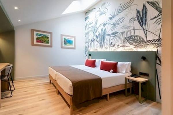 Innenansicht eines Hotelzimmers im DWO Valencia mit grünen Wänden und einem großen Bett.