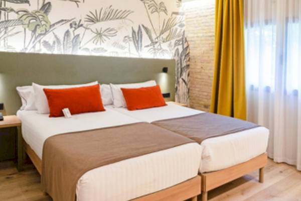 Doppelbett-Zimmer im DWO Valencia Hotel mit tropischem Wanddesign und braunen Laken.