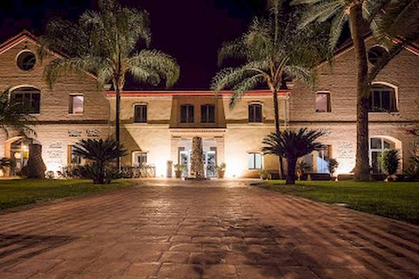 Außenansicht des DWO Valencia Hotels bei Nacht mit beleuchteten Gebäuden und gepflastertem Weg.