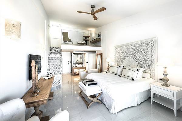 Innenansicht eines Zimmers im Abaton Island Resort & Spa mit weißem Bett, Sofas und Tisch.