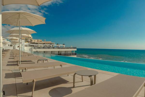 Pool-Terrasse des RH Bayren & Spa Hotels mit Sonnenliegen und Sonnenschirmen am Meer