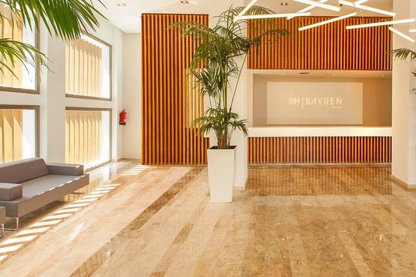Hotellobby des RH Bayren & Spa mit modernem Design, großen Pflanzen und warmem Licht.