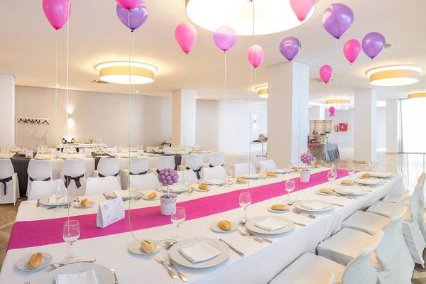 Bankettsaal im RH Bayren & Spa mit mehreren pinken und lilafarbenen Ballons, gedecktem Tisch und weißen Stühlen.