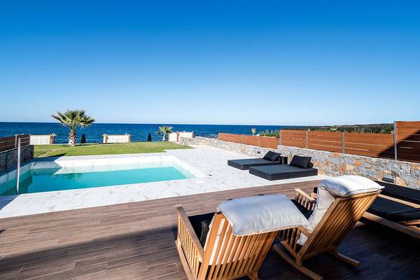 Außenbereich des Abaton Island Resort & Spa mit Pool und Liegestühlen am Meer