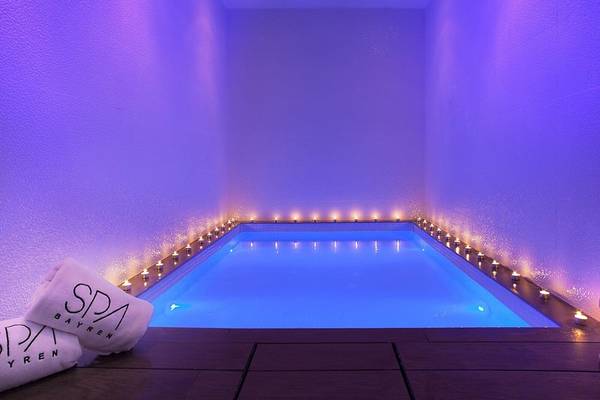 Innenpool des RH Bayren & Spa mit blauer Beleuchtung und brennenden Kerzen