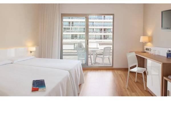 Hotelzimmer im RH Bayren & Spa mit zwei Betten, Schreibtisch und Balkon mit Tisch und Stühlen.