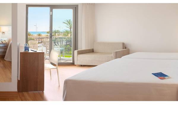 Innenansicht eines Zimmers im RH Bayren & Spa Hotel mit Blick auf den Balkon und das Meer.