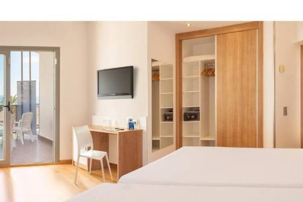 Innenansicht eines Hotelzimmers im RH Bayren & Spa, mit zwei Betten, Schreibtisch, Fernseher und Balkonzugang.