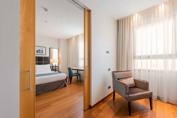 Innenansicht eines Hotelzimmers im Eurostars Grand Valencia, mit Bett, Schreibtisch, Stuhl und Fenstern.