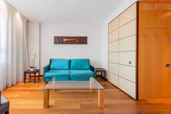 Wohnzimmer im Eurostars Grand Valencia mit blauer Couch und Glastisch.