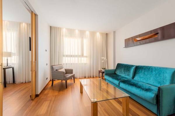 Eurostars Grand Valencia Innenbereich Wohnzimmer mit blauem Sofa, Couchtisch und grauem Sessel.