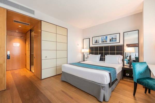 Innenansicht eines Hotelzimmers im Eurostars Grand Valencia mit Doppelbett, Nachttischen und Spiegel.