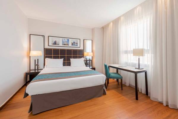 Hotelzimmer im Eurostars Grand Valencia mit Bett, Schreibtisch, Stühlen und Lampen.