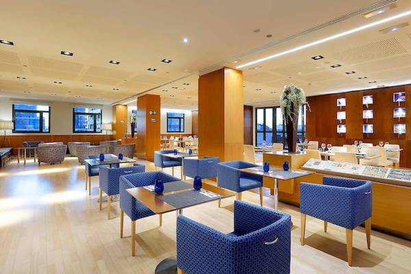 Innenbereich des Eurostars Grand Valencia Hotels mit blauen Stühlen und Tischen, Holzboden und moderner Einrichtung.