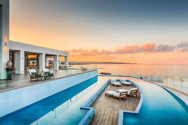 Außenpool des Abaton Island Resort & Spa bei Sonnenuntergang mit Blick auf das Meer.