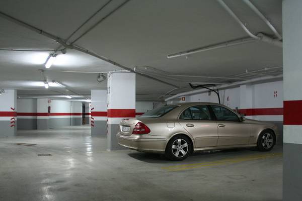 Unterirdischer Parkplatz mit einer beigefarbenen Limousine, gekennzeichnet durch rote und weiße Säulen.