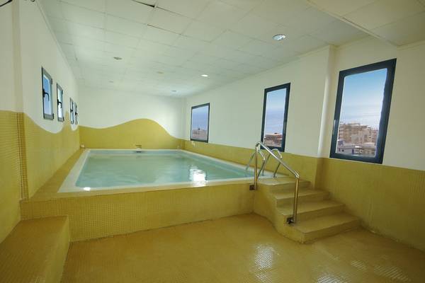 Schwimmbecken im Hotel Principal Afilliated by RH mit gelben Wänden und Fenstern.
