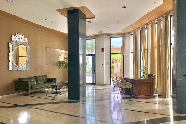 Lobby des Principal Afilliated by RH Hotels mit grüner Couch und Holzschreibtisch